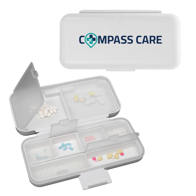 A white compact pill organiser with multiple compartments, featuring a logo on the lid and various coloured pills inside.