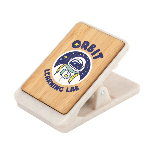 A bamboo magnetic clip with a design featuring an astronaut surrounded by stars, set on a speckled white base.