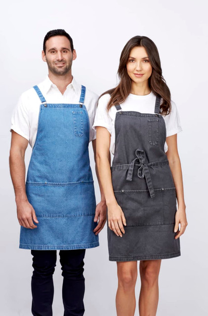 A denim bib apron in blue on a man and a grey apron on a woman, both featuring pockets and ties.
