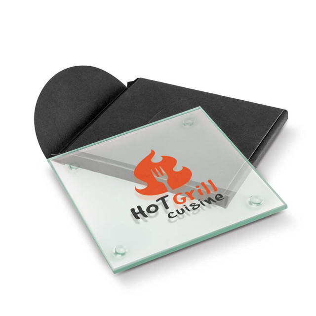 A square glass coaster in clear colour, featuring a logo and presented in a black packaging.