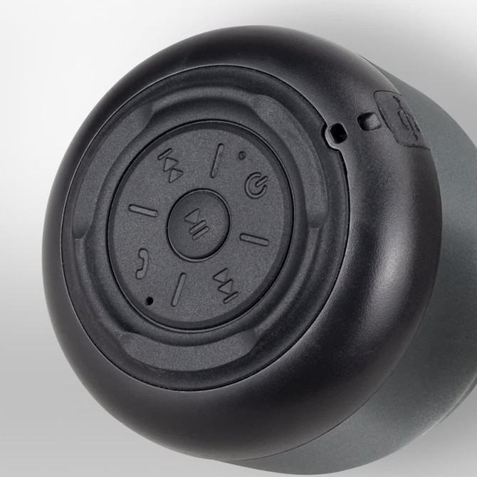 Auris Bluetooth speaker featuring a round, black control panel with buttons for playback, located on a grey body.