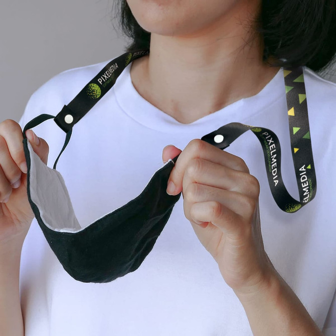 A person holding a black mask attached to a colourful lanyard with a logo.