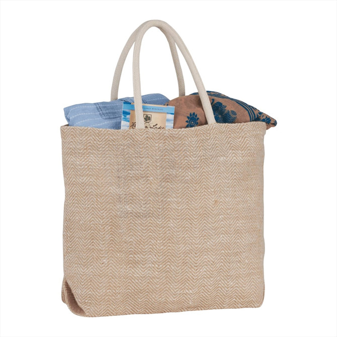 A herringbone-patterned jute tote in beige, filled with a blue and patterned fabric, featuring two handles and a logo.
