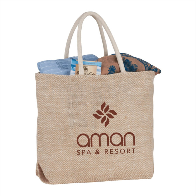 A herringbone-patterned jute tote bag in natural tones with two handles and a logo.