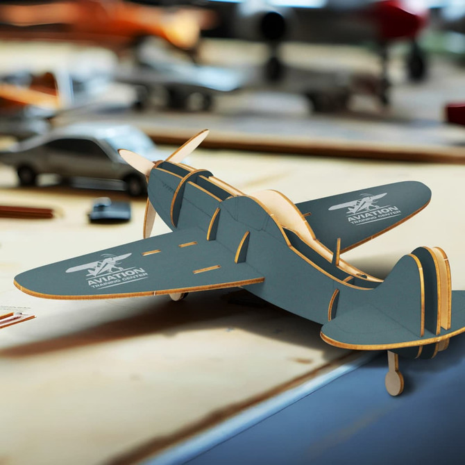 A wooden model aircraft in grey, featuring intricate details and a logo, displayed on a workspace with tools.