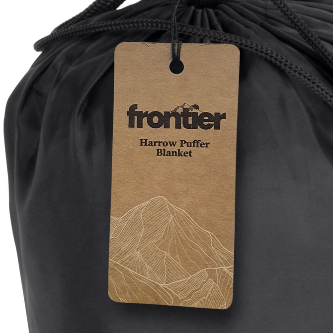 A black puffer blanket with a tag featuring a logo and mountain design.