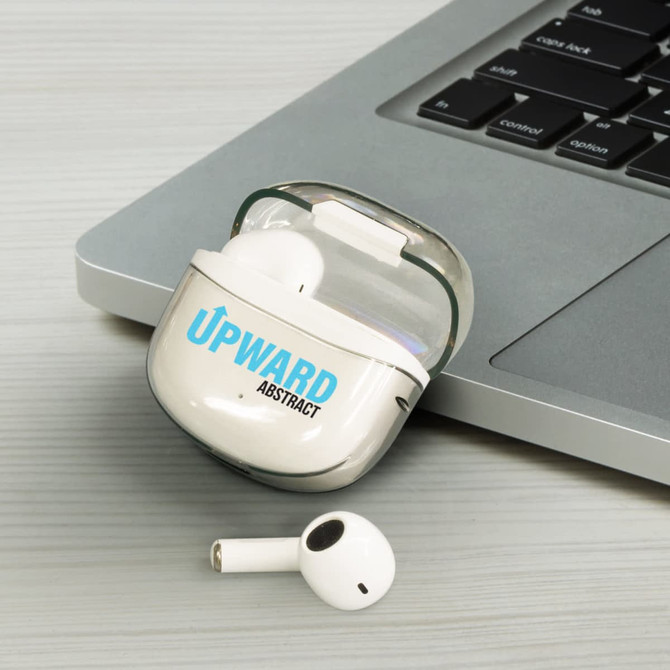 A pair of white Bluetooth earbuds in a charging case, placed next to a laptop on a grey surface.