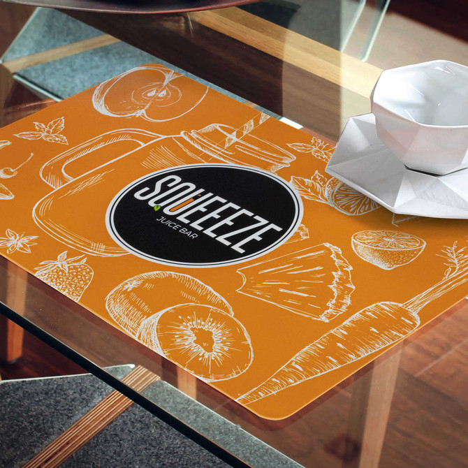 A vibrant orange place mat featuring fruit and vegetable illustrations, with a logo in the centre.