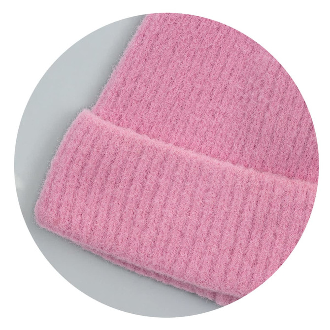 A pink brushed kids beanie with a textured, ribbed cuff and soft fabric. It features a logo on the tag.