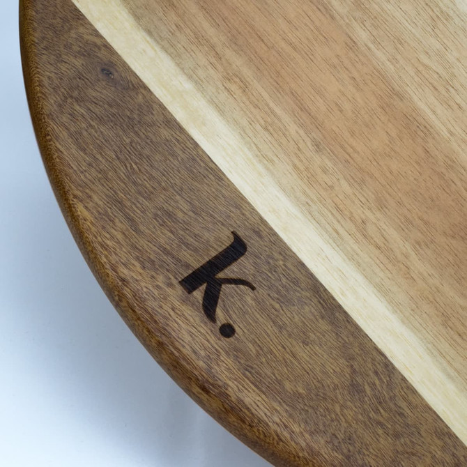 A round wooden Lazy Susan with a contrasting light wood stripe and a small logo engraved on the edge.