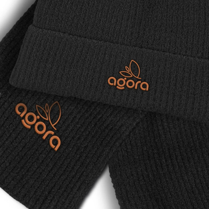 A black scarf and beanie set featuring an orange logo. The beanie has a ribbed texture.