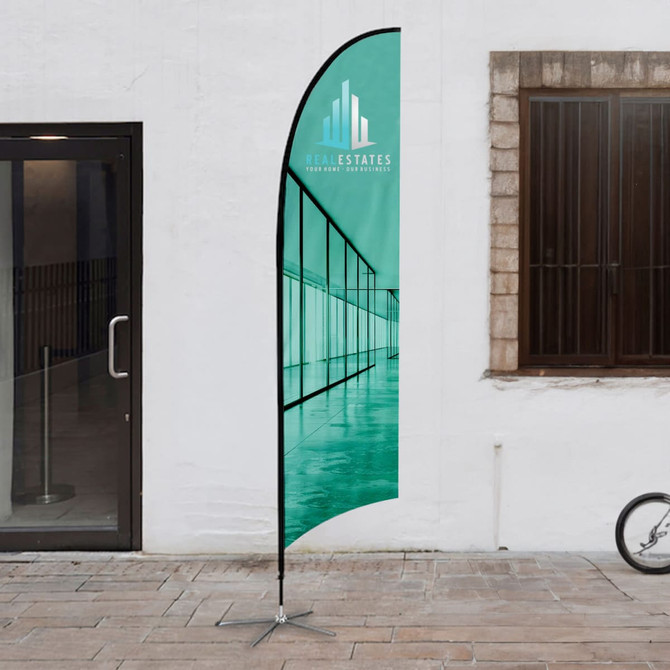 A medium feather flag kit with a teal design, featuring a logo, set up outdoors.