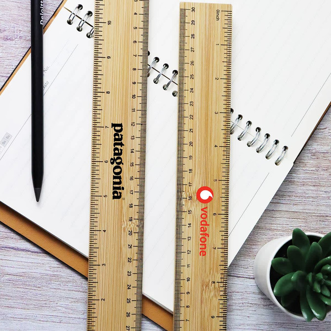 Apex Bamboo Ruler in natural wood finish, featuring a logo, placed beside a notebook and a black pencil.