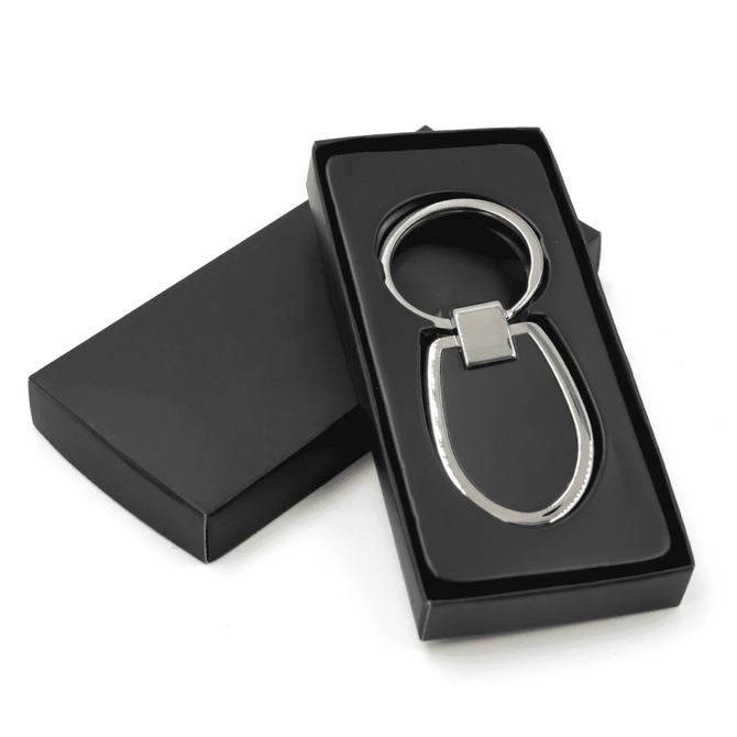 A sleek silver keychain with an oval design, presented in a black box.