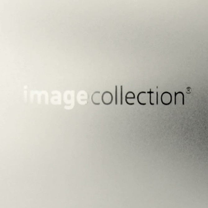 A sleek, metallic silver business card holder features a subtle logo and a refined, glossy finish.