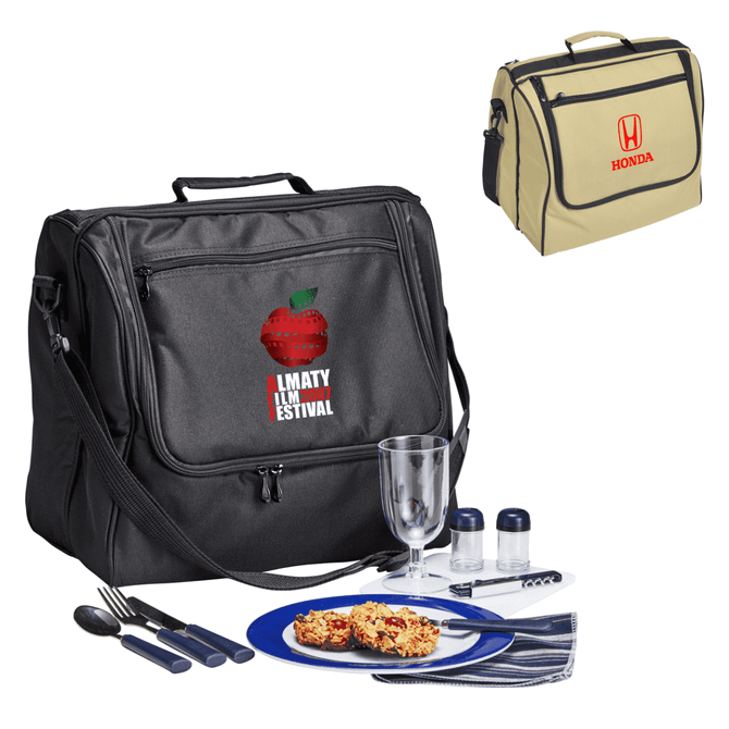 A black picnic bag with cutlery, a plate of food, and a drink glass. A beige bag with a logo is also visible.