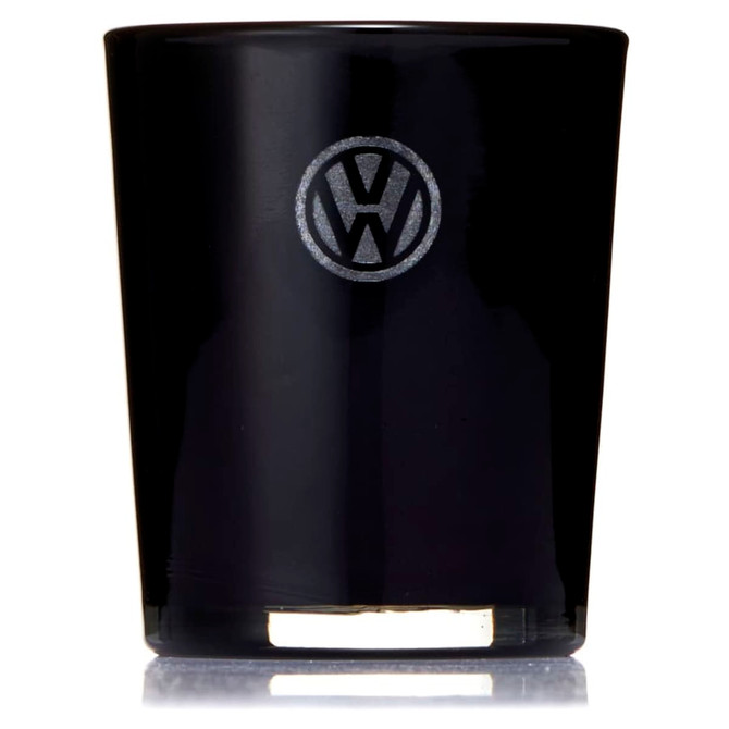 A glass candle in a sleek black holder with a logo on the front. The candle features a gold base.