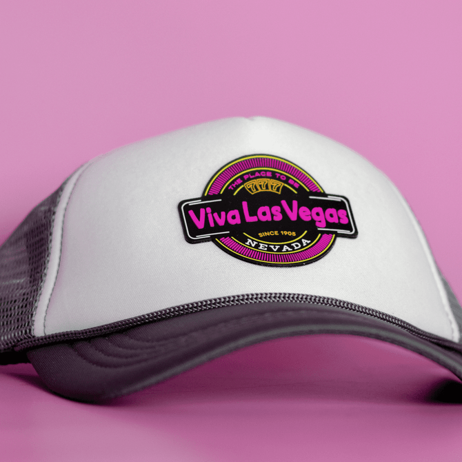 A grey and white cap featuring a round logo with vibrant pink and black elements.