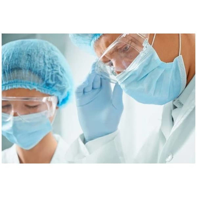 A medical professional wearing a blue face mask and protective eyewear, alongside another person in similar attire.