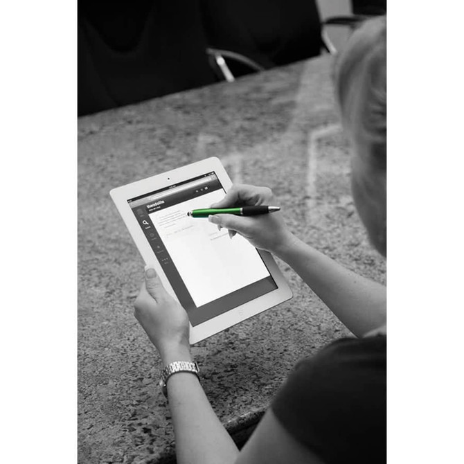 A stylus pen in green is being used on a tablet, with a person’s hand visible. The background features a textured surface.