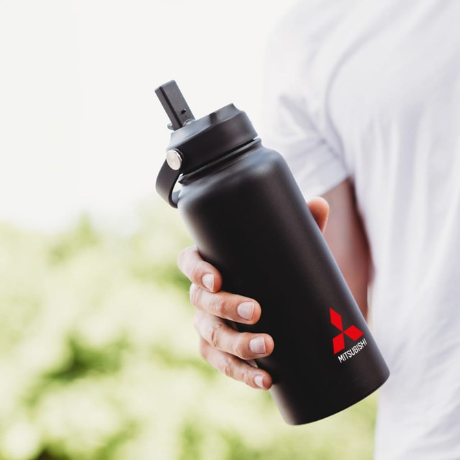 A black drink bottle with a straw lid, held by a person, featuring a logo.