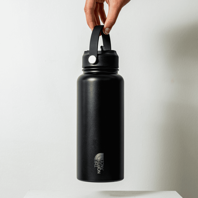 A drink bottle in matte black, featuring a handle and a logo, designed for durability and convenience.