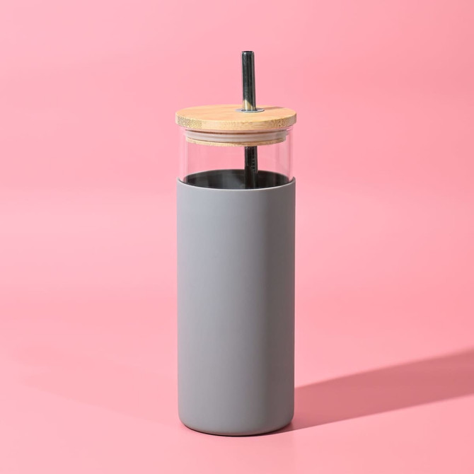 A drink bottle with a grey silicone sleeve, clear glass body, and wooden lid, featuring a reusable straw.