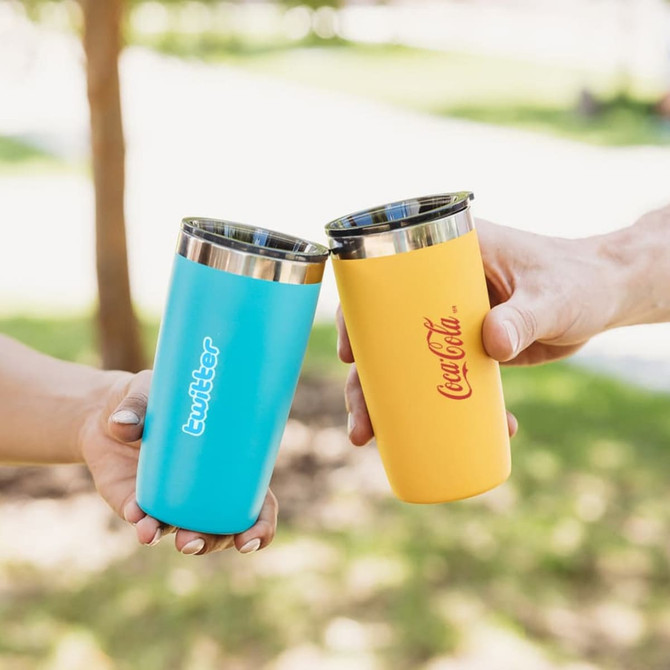 A drink bottle in blue and yellow, featuring logos, with stainless steel interiors, held by two hands.