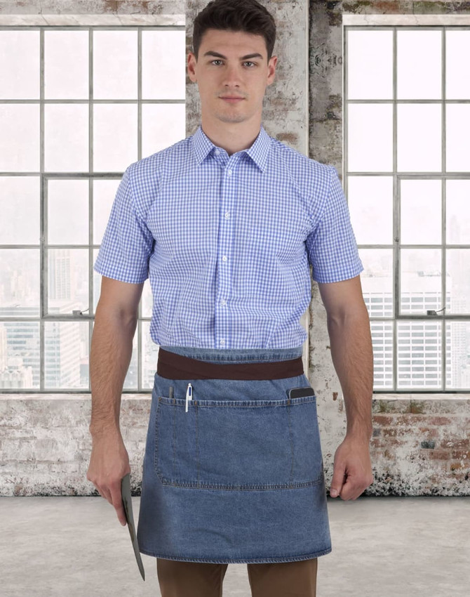 A denim half apron with a brown waistband, worn by a person in a blue checked shirt, against a city skyline backdrop.