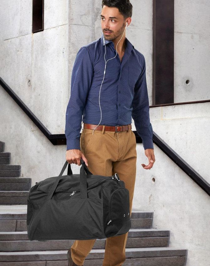 A red duffle bag with a zippered compartment and a pair of shoes resting against it. The bag has a logo.