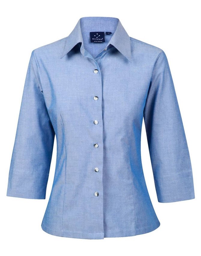 A light blue chambray shirt with 3/4 sleeves and a button-up front. The shirt features a collar and has a logo.