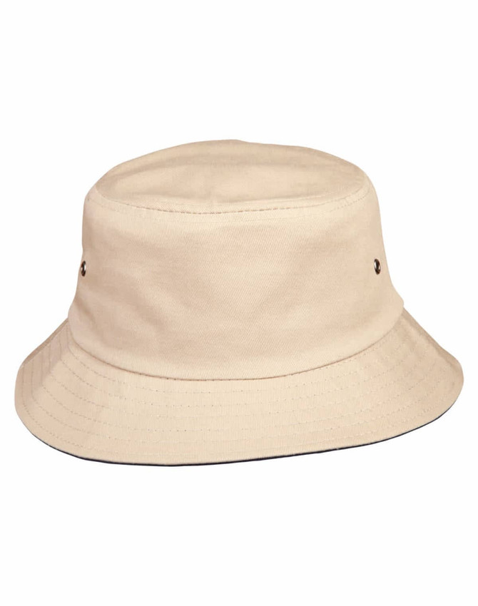 A cream bucket hat with a wide brim and metal eyelets. It features a simple design and has a logo on it.