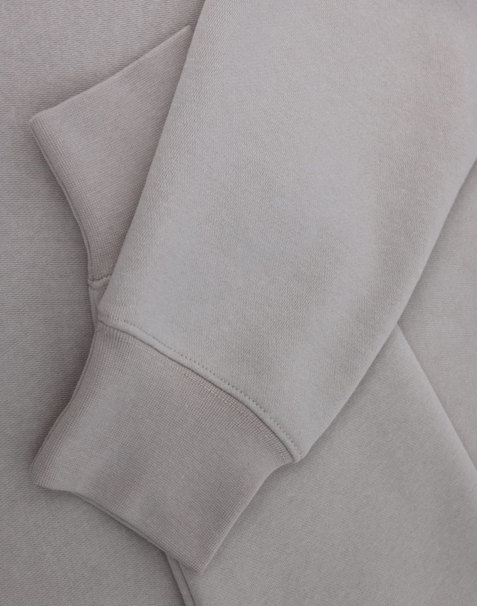A light grey crewneck sweatshirt with a soft texture, featuring long sleeves and a cuffed hem.