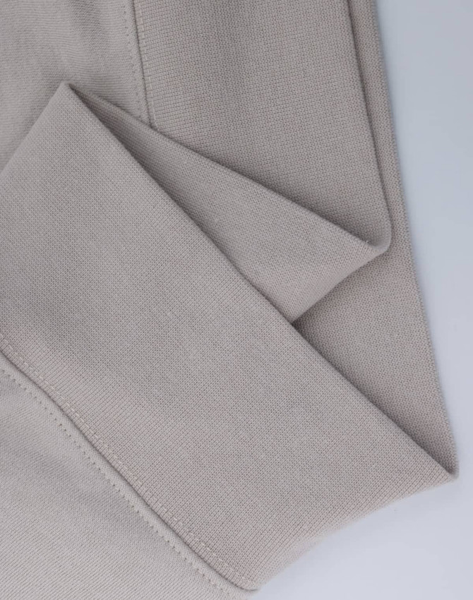A close-up of a light beige polar fleece jumper featuring a half-zip collar. It has a simple design with a logo.