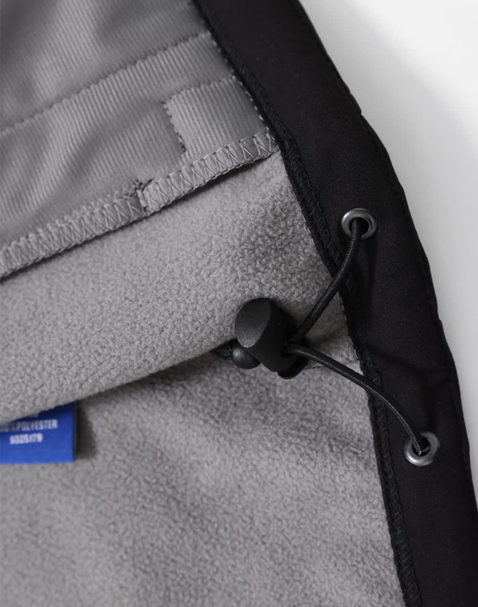 A close-up of a black men's softshell full zip hoodie interior, featuring a grey fleece lining and adjustable drawcord.