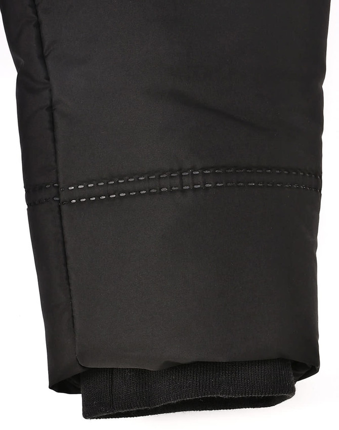 A close-up of a black sustainable parka jacket featuring a seamless design and detailed stitching at the cuff.