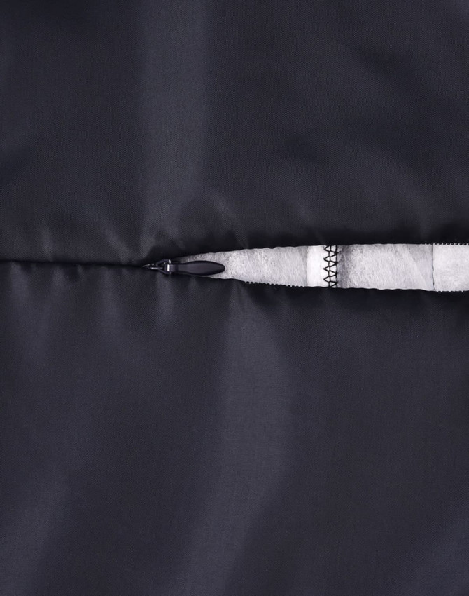 A close-up of a black insulated puffer jacket featuring a zippered pocket and a soft lining.