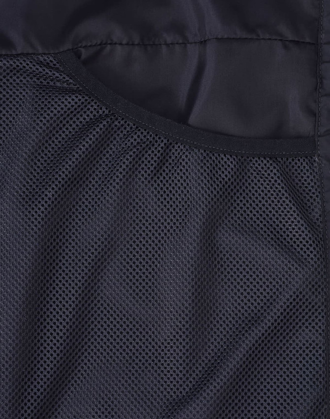A black textured fabric featuring mesh detailing, part of a men's sustainable insulated puffer jacket.