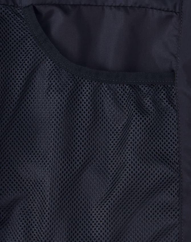 A close-up of a black insulated puffer jacket showing a mesh pocket. The jacket has a smooth fabric finish and a logo.
