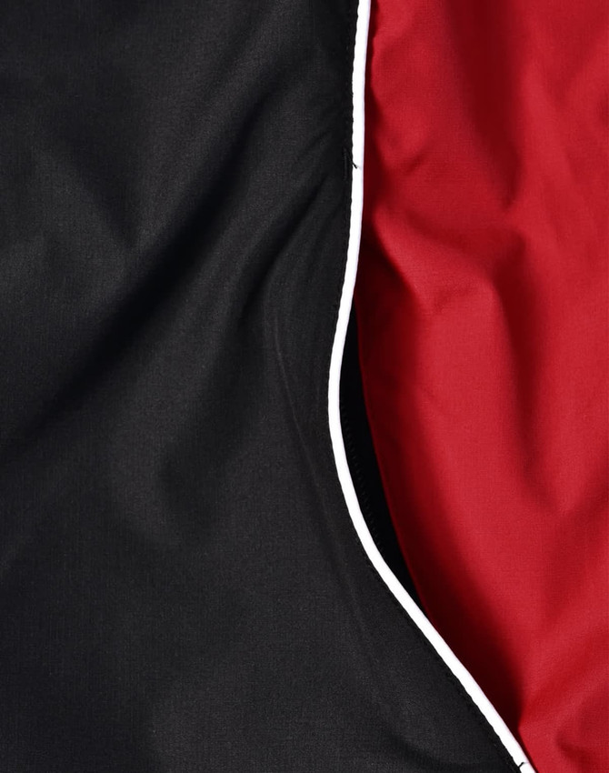 A close-up of a unisex jacket featuring black and red fabric with contrasting white piping.