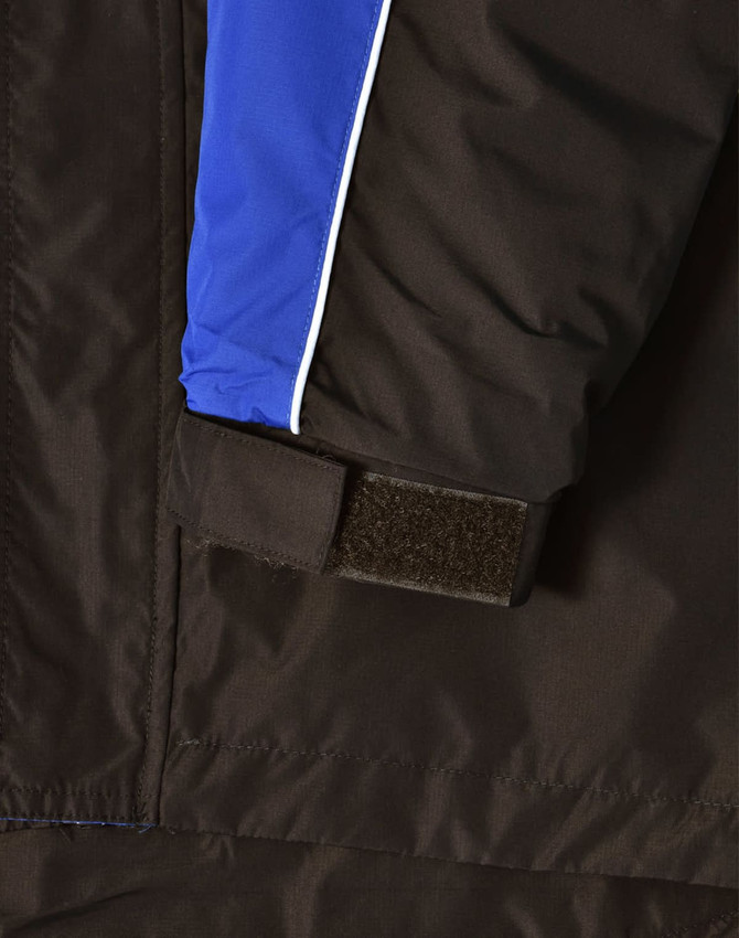 A close-up of a unisex jacket featuring black fabric with blue and white accents and a Velcro detail.