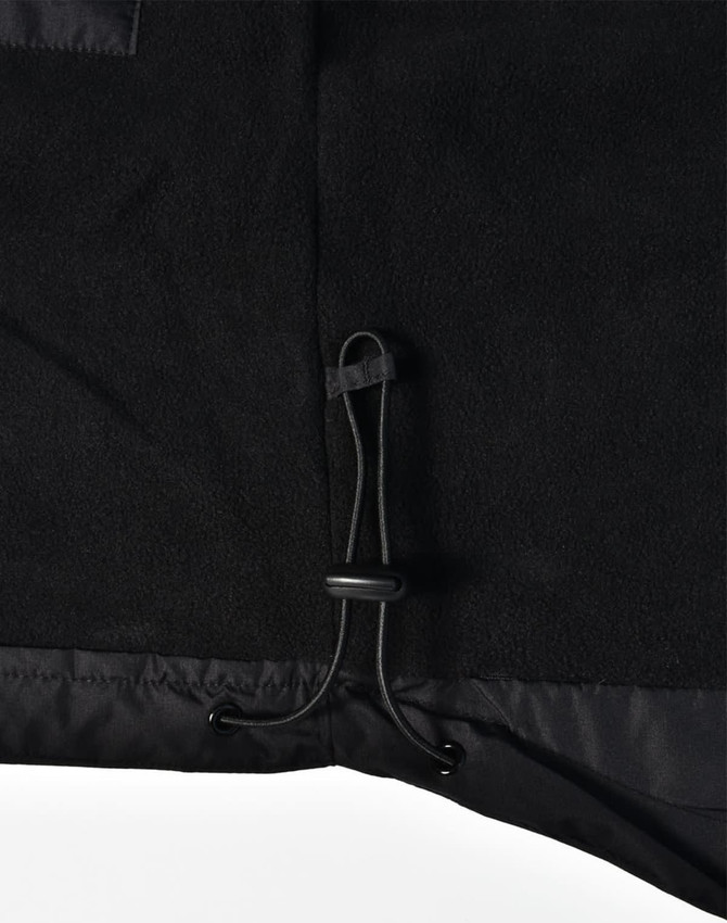 Detail of a black fleece jacket featuring a drawstring adjustment at the hem. The jacket has a logo.