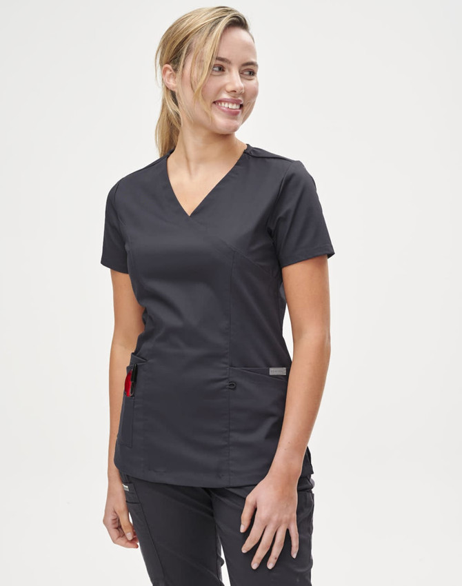 A solid black short-sleeve scrub top worn by a smiling woman, featuring a v-neck and pockets.