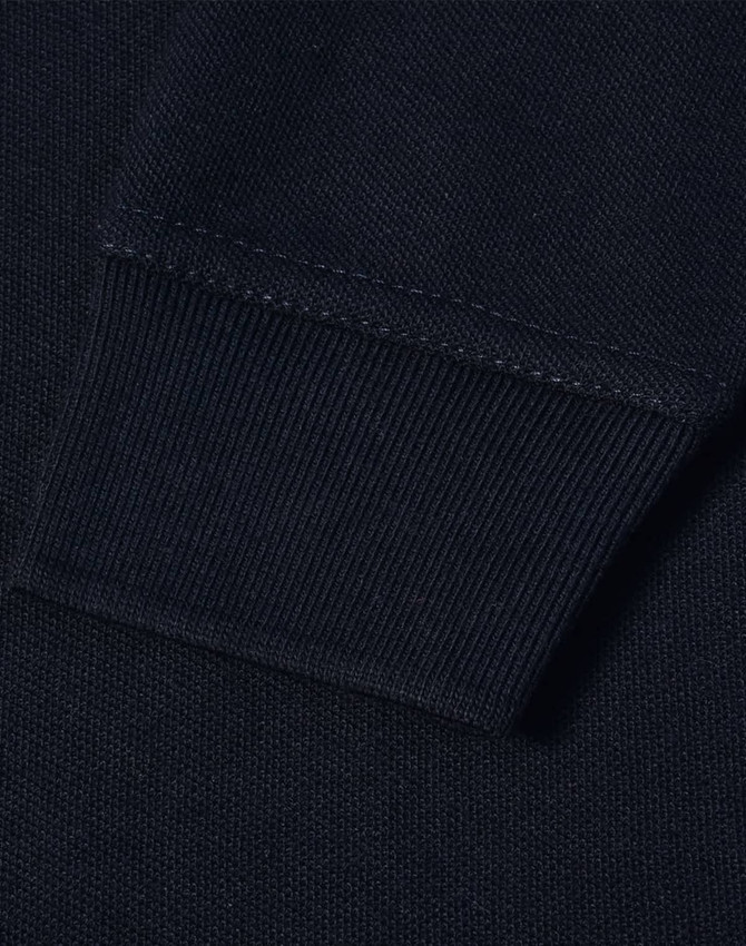 A close-up view of the cuff of a navy blue polo shirt featuring a ribbed design and a logo.
