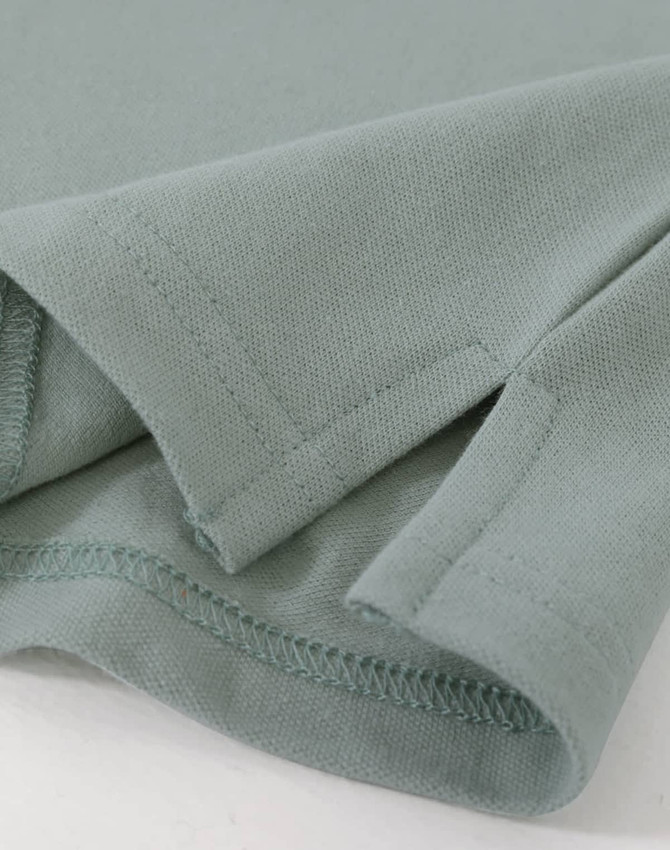 A close-up of a ladies cotton stretch polo in a soft green colour, highlighting the fabric and stitching details.