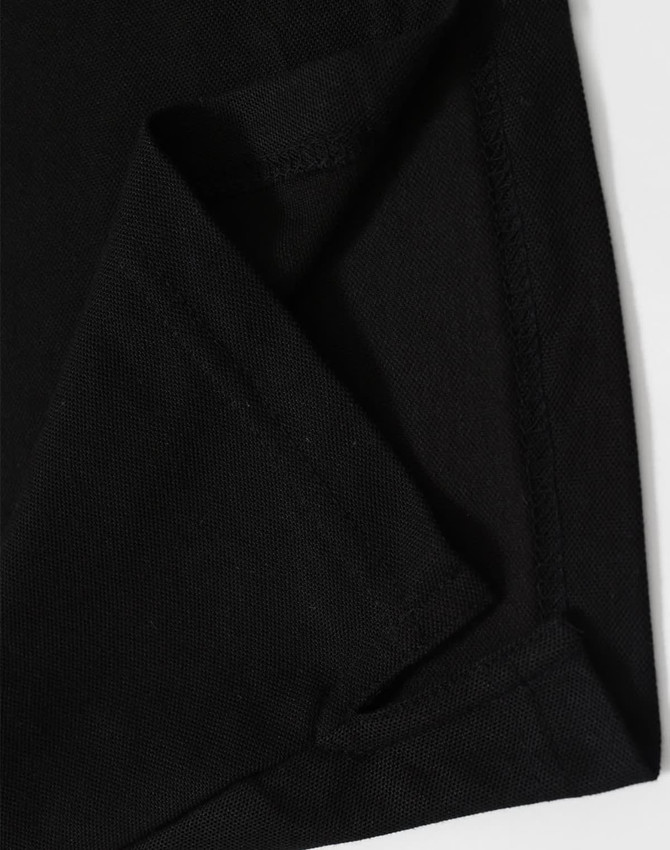 A close-up of black fabric showcasing a folded corner, featuring stitching details and a hidden pocket.