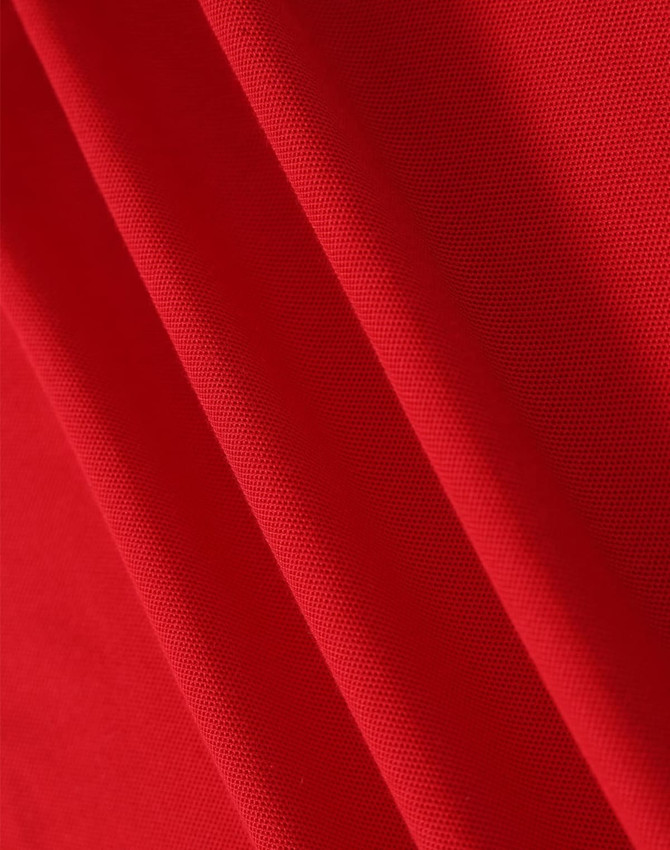A red fabric with a textured surface, showcasing the material of a polo shirt. It has a logo in the corner.