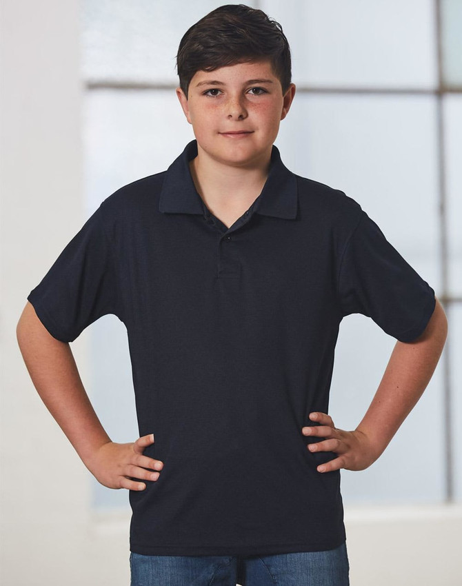 A young boy in a black short-sleeve polo shirt stands confidently with his hands on his hips.