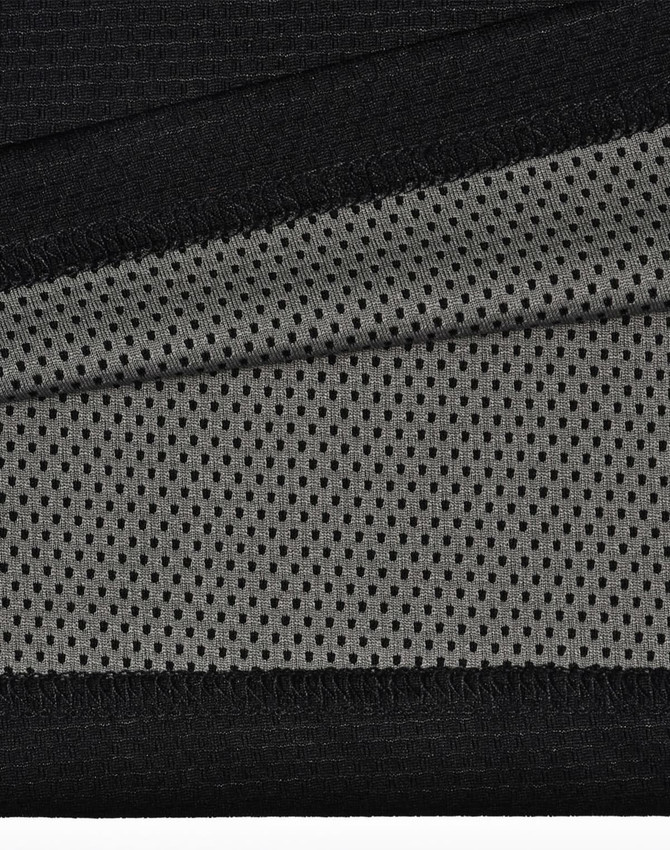 A close-up of black and grey fabric, featuring a textured surface and mesh pattern, ideal for polo shirts.