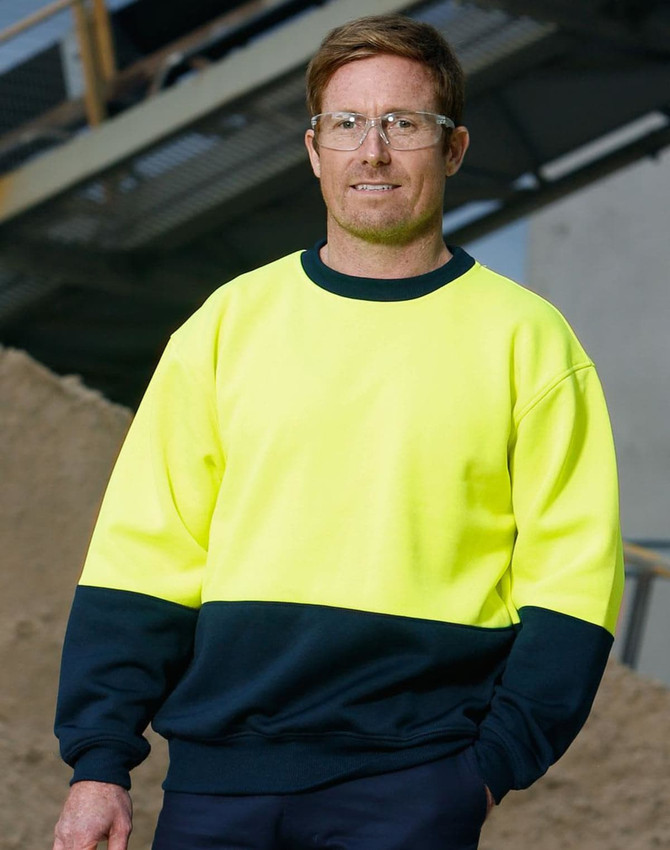 A Hi-Vis two tone safety windcheater in bright yellow and navy, worn by a man with safety glasses.